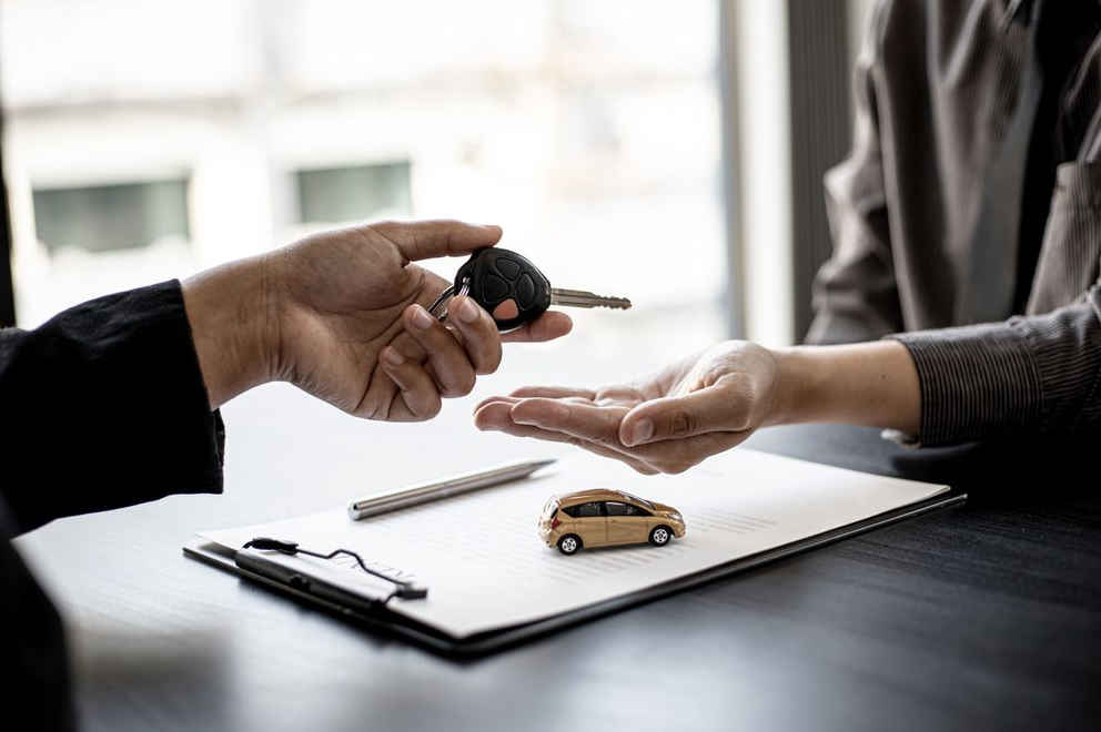 An individual handing car keys over to a new buyer.
