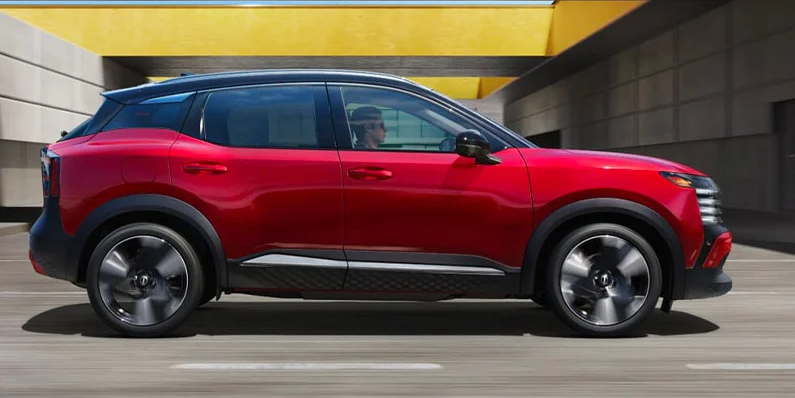 A red 2025 Nissan Kicks driving down the road.