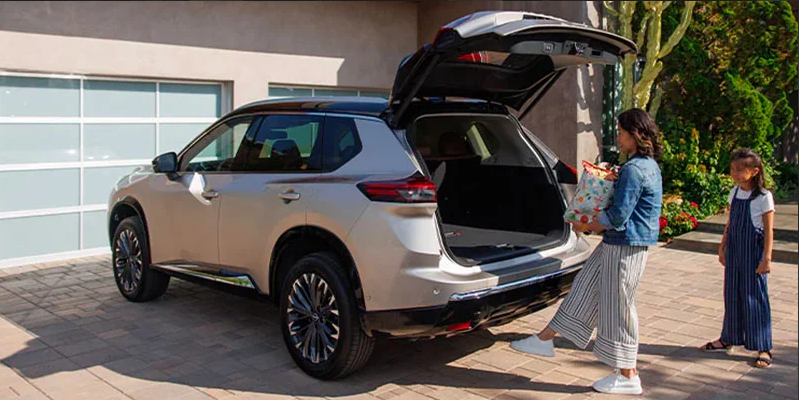 A photo of a woman loading bags in to the back of a 2025 Nissan Rogue.