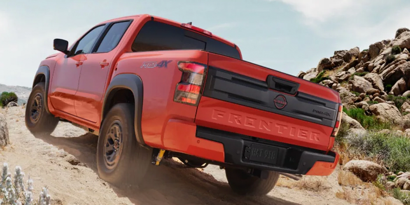 2026 Red Nissan Frontier climbing rocks. 